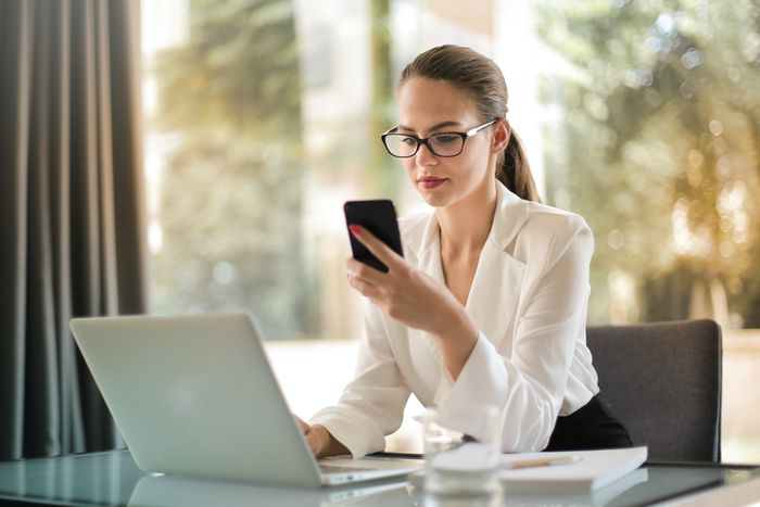 A person using a smartphone and a laptop.