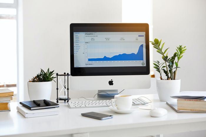 A computer placed on a desk displaying a line graph by Serpstat 